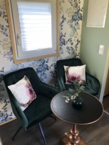 Die Sitzecke mit Sesseln und Tisch vor bunter Blumentapete