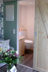 Die rustikale Holzschiebetür zum Bad des Tiny Houses Rhein