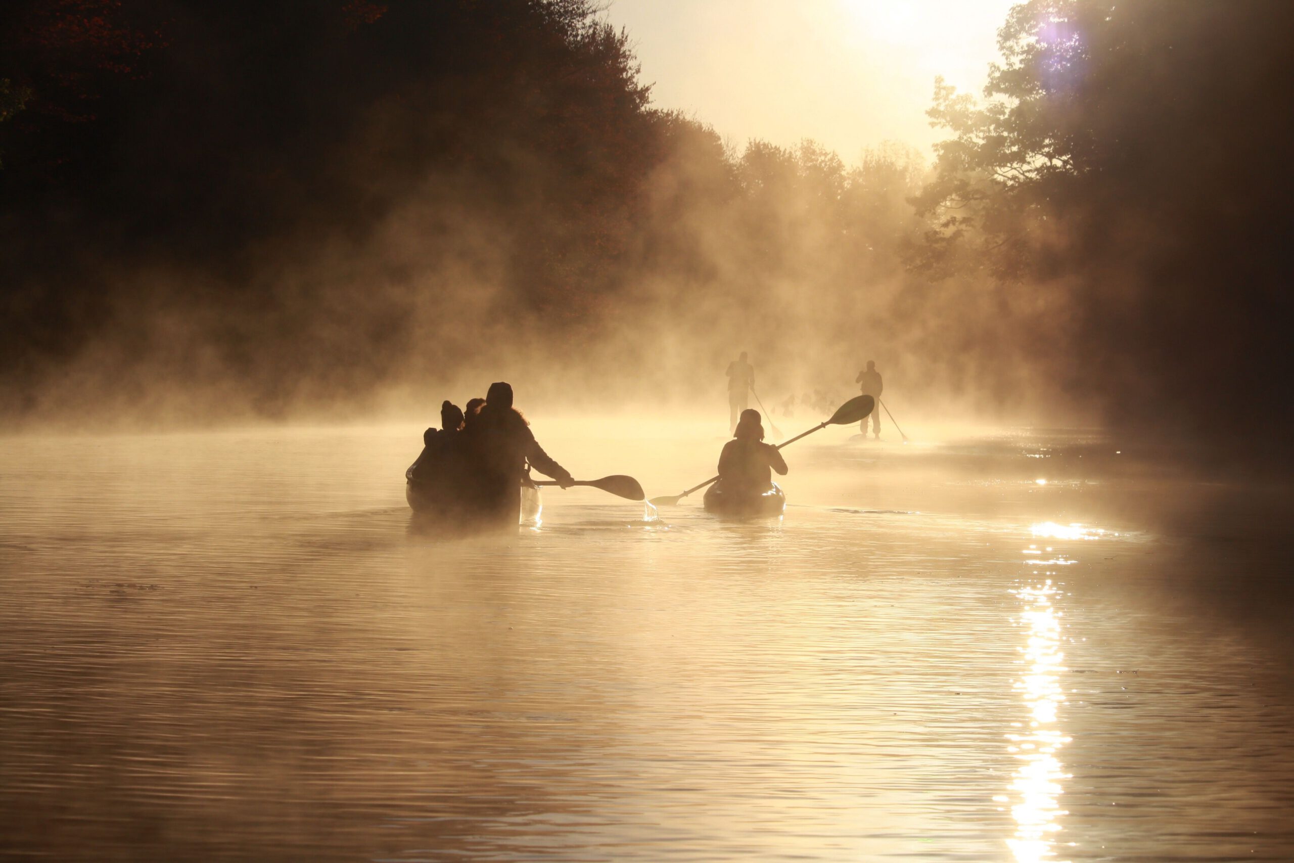 Kanufahrer paddeln im Morgennebel auf einem Fluss